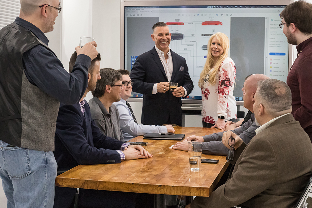 Emil Pilacik, Jr. and team smiling and laughing during IT team meeting.
